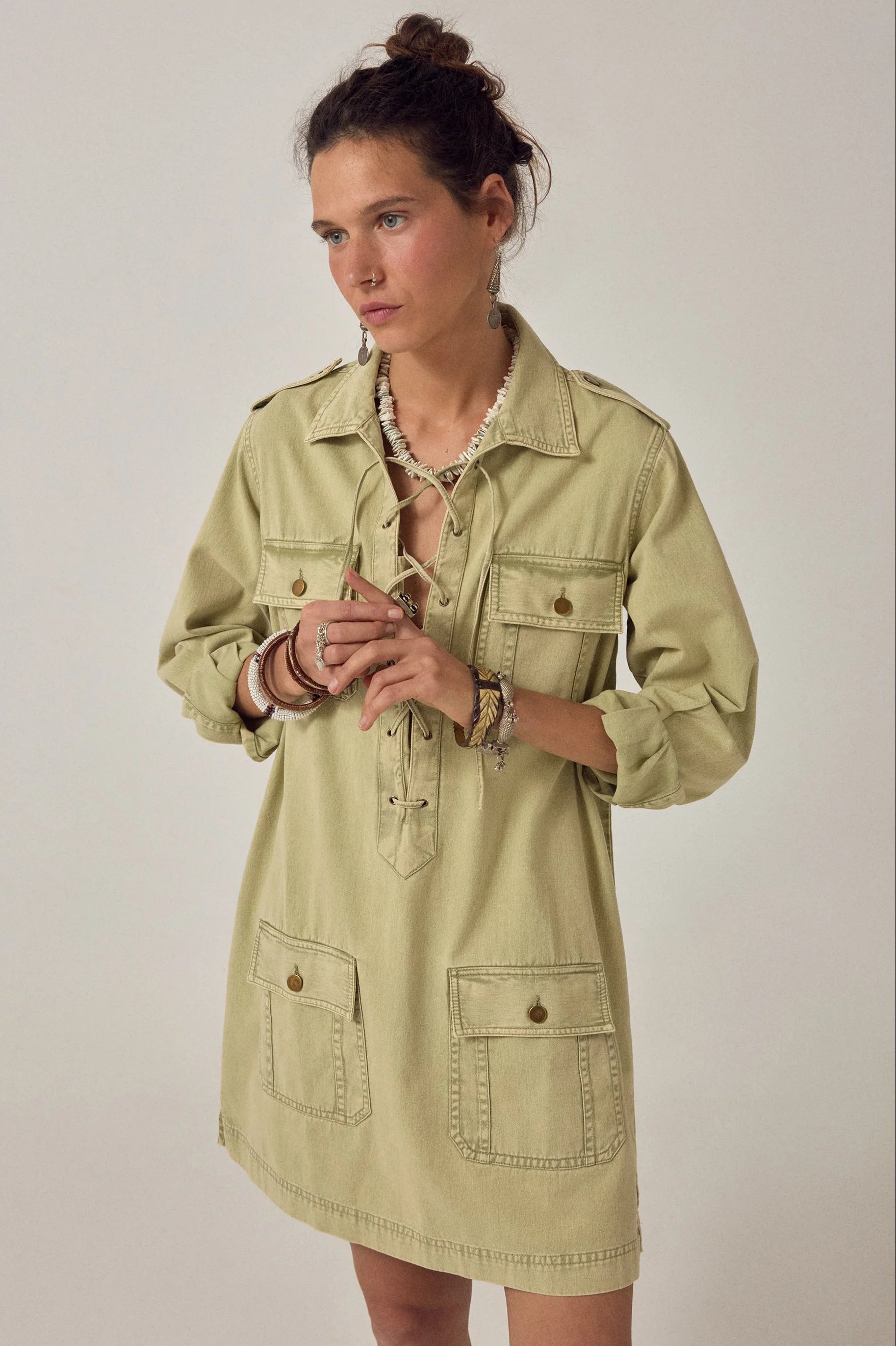 Angled front view of the Thalassa Short Dress in Army Khaki with utility-inspired flap pockets, lace-up neckline, and relaxed cotton twill silhouette.