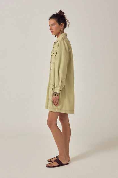 Side profile of the Thalassa Short Dress in Army Khaki featuring a relaxed fit, long sleeves, and structured utility-inspired silhouette.