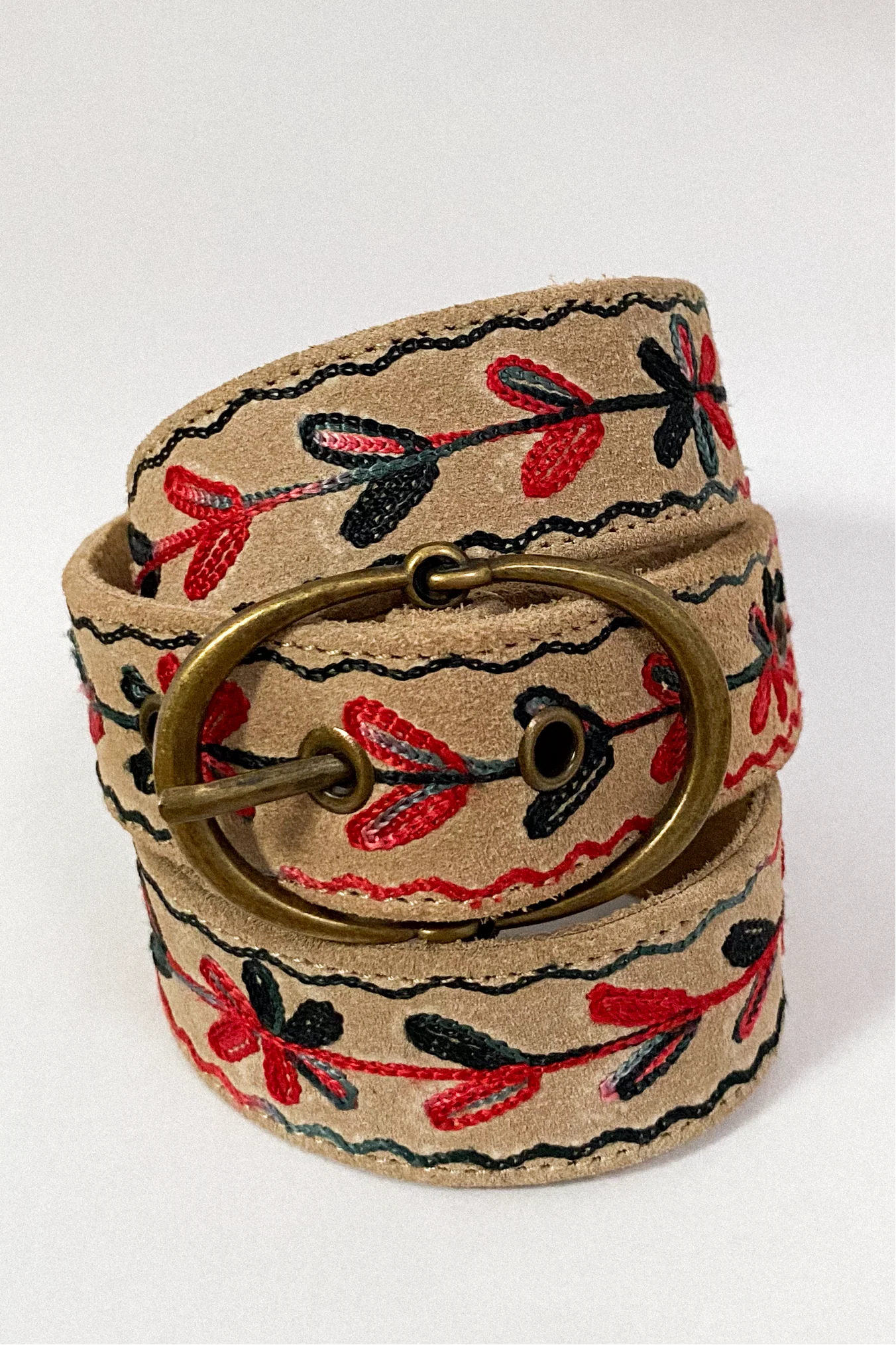 Rolled view of the Thar Belt - Karma Thread highlighting the brass buckle, desert suede leather, and black and red embroidery.