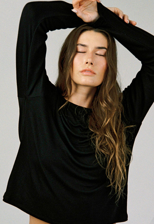 Model wearing The Cozy Tee in Black, featuring a relaxed fit, drop shoulders, and long sleeves