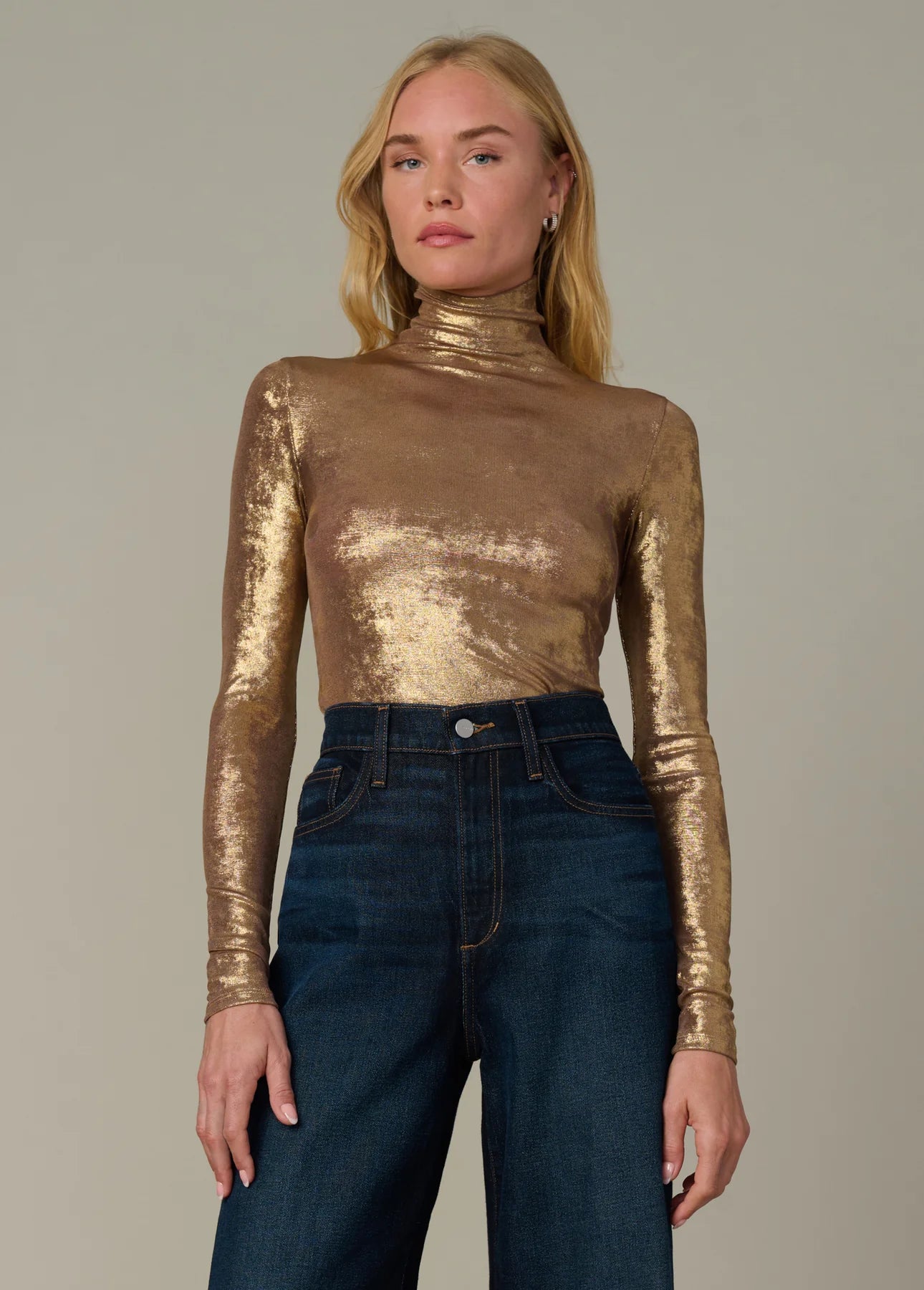 Full-length view of the metallic gold Tony Top styled with dark denim jeans and a modern funnel neckline.
