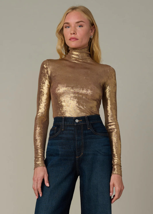 Full-length view of the metallic gold Tony Top styled with dark denim jeans and a modern funnel neckline.