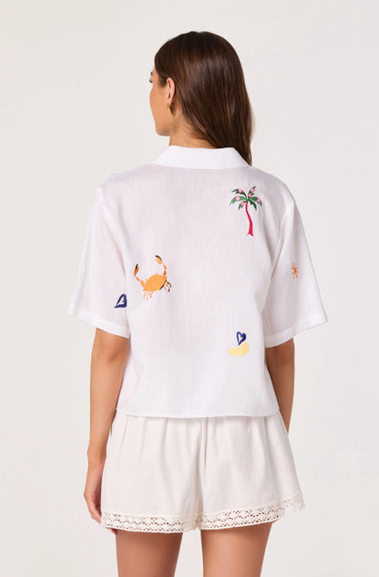 Back view of the Vesa Embroidered Linen Button-Up Top showing the relaxed cropped silhouette, short sleeves, and colorful embroidery across the back.