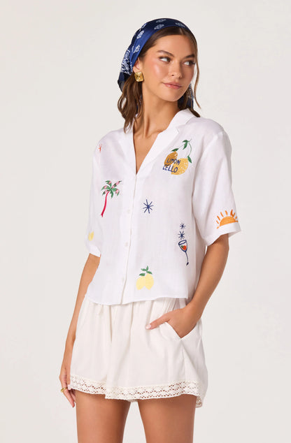Model wearing the Vesa Embroidered Linen Button-Up Top with a blue scarf and white shorts, showing the relaxed fit and colorful embroidery.