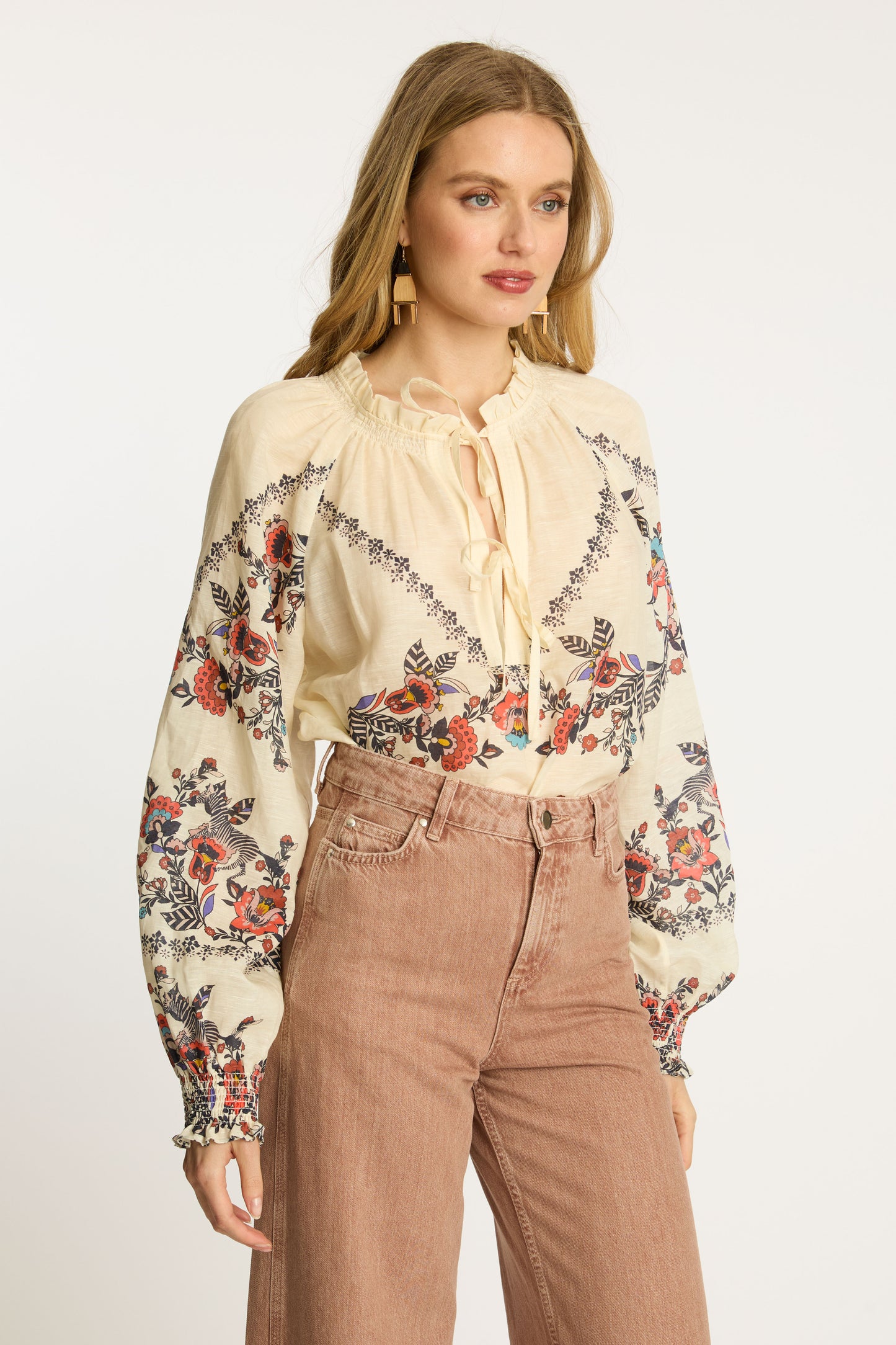 Angled portrait of the Vickie Top in Zebra Leaf showing the colorful embroidered floral print, voluminous sleeves, ruffle trim neckline, and relaxed feminine silhouette.