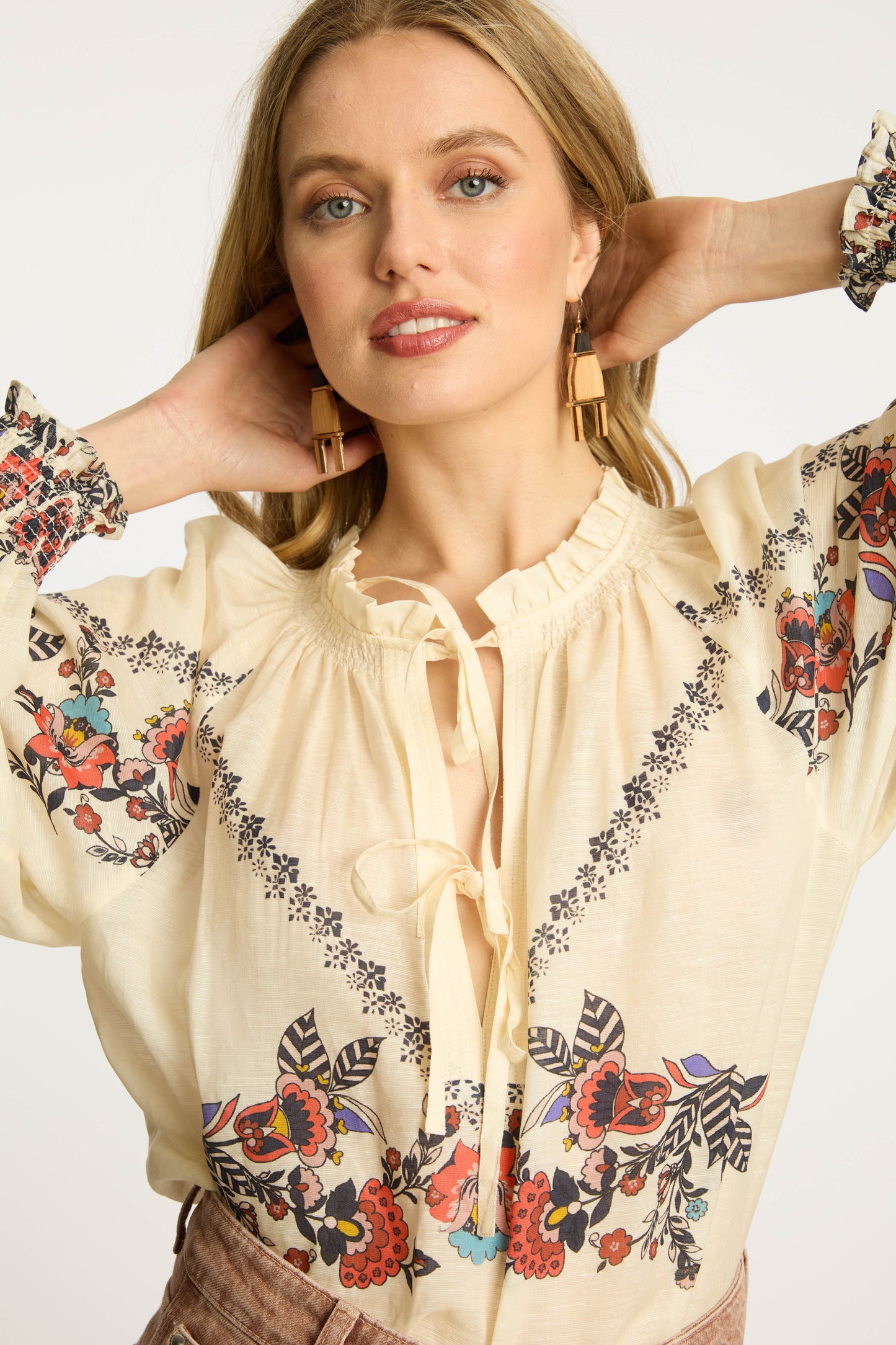 Close-up of the Vickie Top in Zebra Leaf featuring floral embroidery, ruffle-trim neckline, tassel tie details, and soft cream fabric with voluminous sleeves.