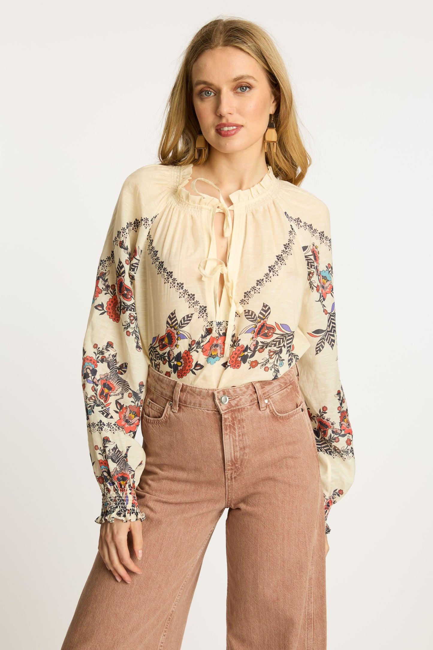 Portrait view of the Vickie Top in Zebra Leaf featuring embroidered floral motifs, soft cream fabric, tassel tie neckline, and relaxed boho-chic styling.