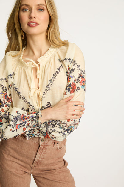 Detailed angled view of the Vickie Top in Zebra Leaf showcasing colorful floral embroidery, voluminous sleeves, smocked cuffs, and feminine ruffle neckline.