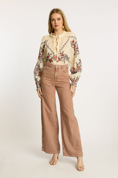Full front styling view of the Vickie Top in Zebra Leaf paired with blush wide-leg denim, featuring colorful embroidery, tassel tie accents, and bohemian-inspired sleeves.