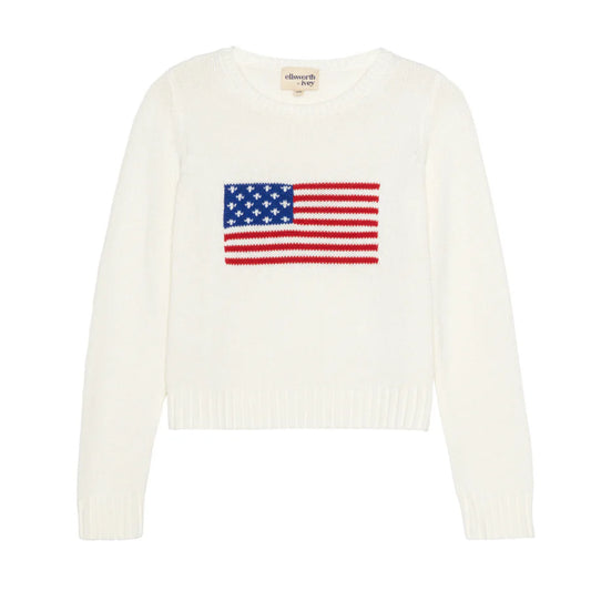 A white cropped crewneck sweater featuring a red, white, and blue American flag intarsia design across the front, with long sleeves and ribbed trim at the neckline, cuffs, and hem.