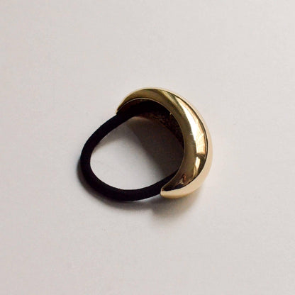 Front angled view of a wide gold crescent metal cuff hair tie with a black elastic.