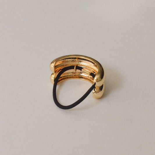 Back view of the gold double arch metal ponytail cuff with attached black elastic.