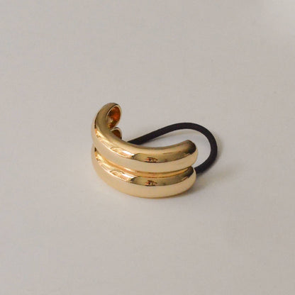 Gold wide double arch metal ponytail hair tie with black elastic shown from the front.