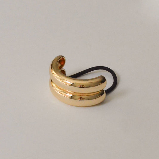 Gold wide double arch metal ponytail hair tie with black elastic shown from the front.