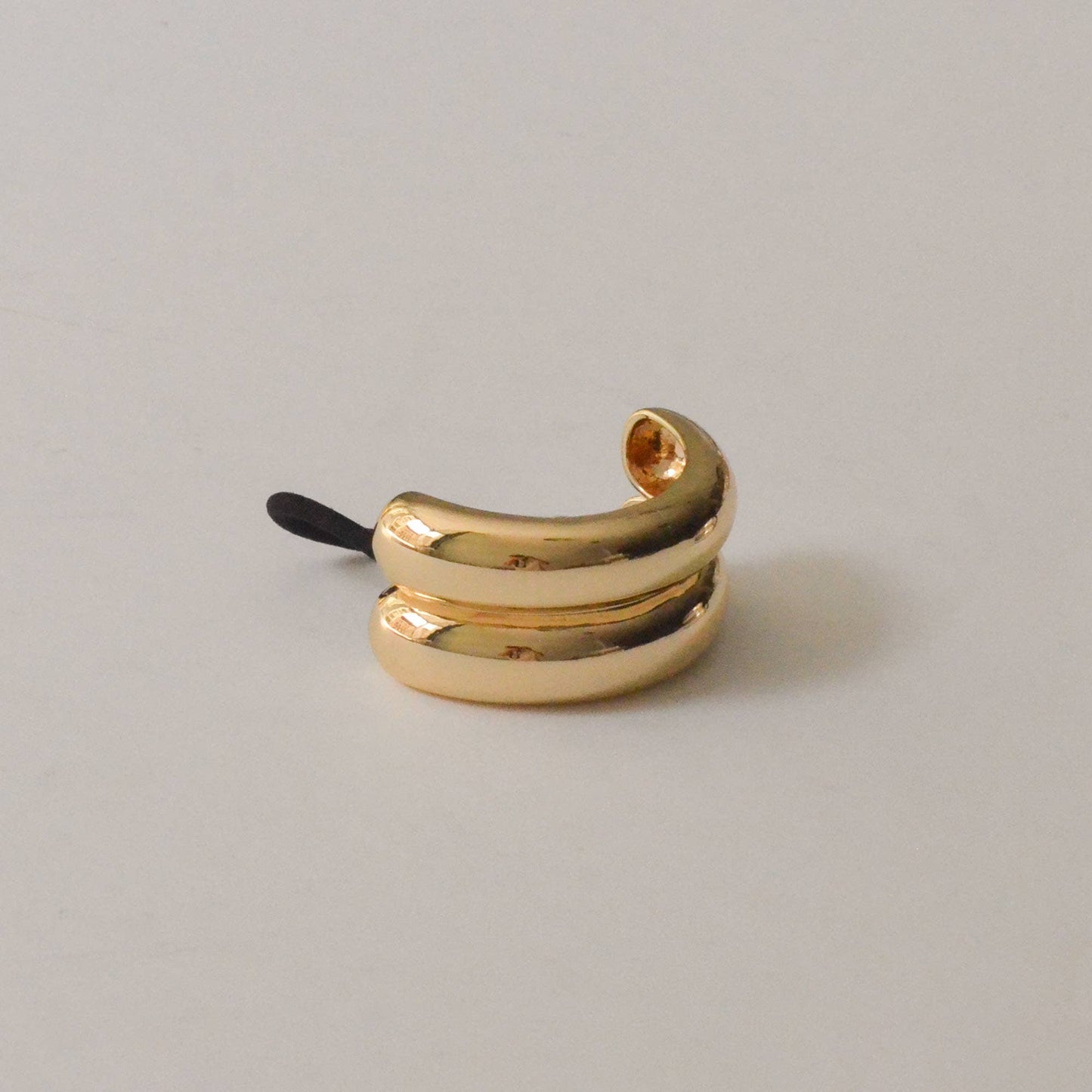 Side view of the polished gold metal ponytail cuff featuring a smooth double arch design.