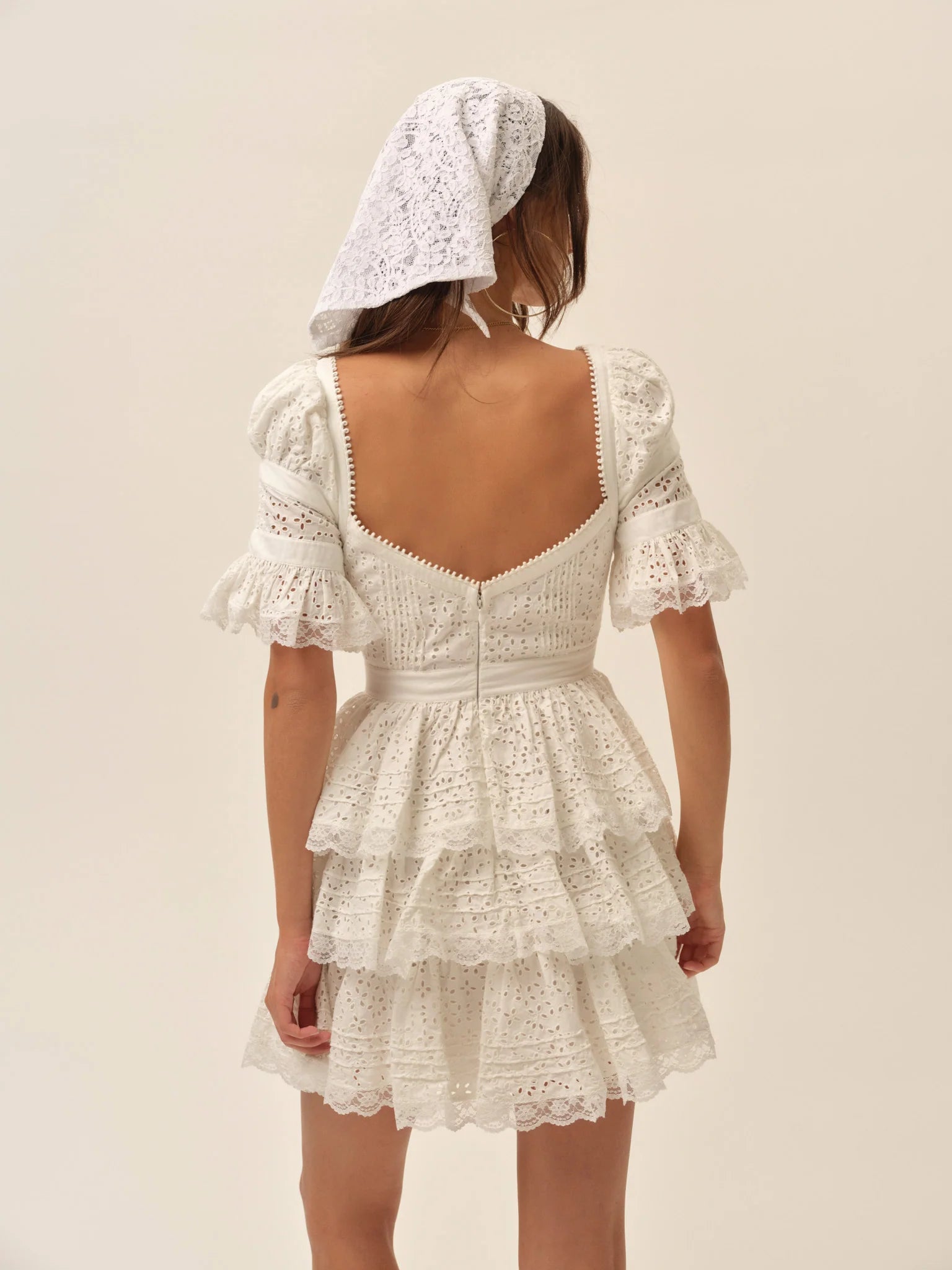 Back view of the Willa Mini Dress in white with puff sleeves, fitted bodice, lace trim details, and layered ruffle mini skirt.