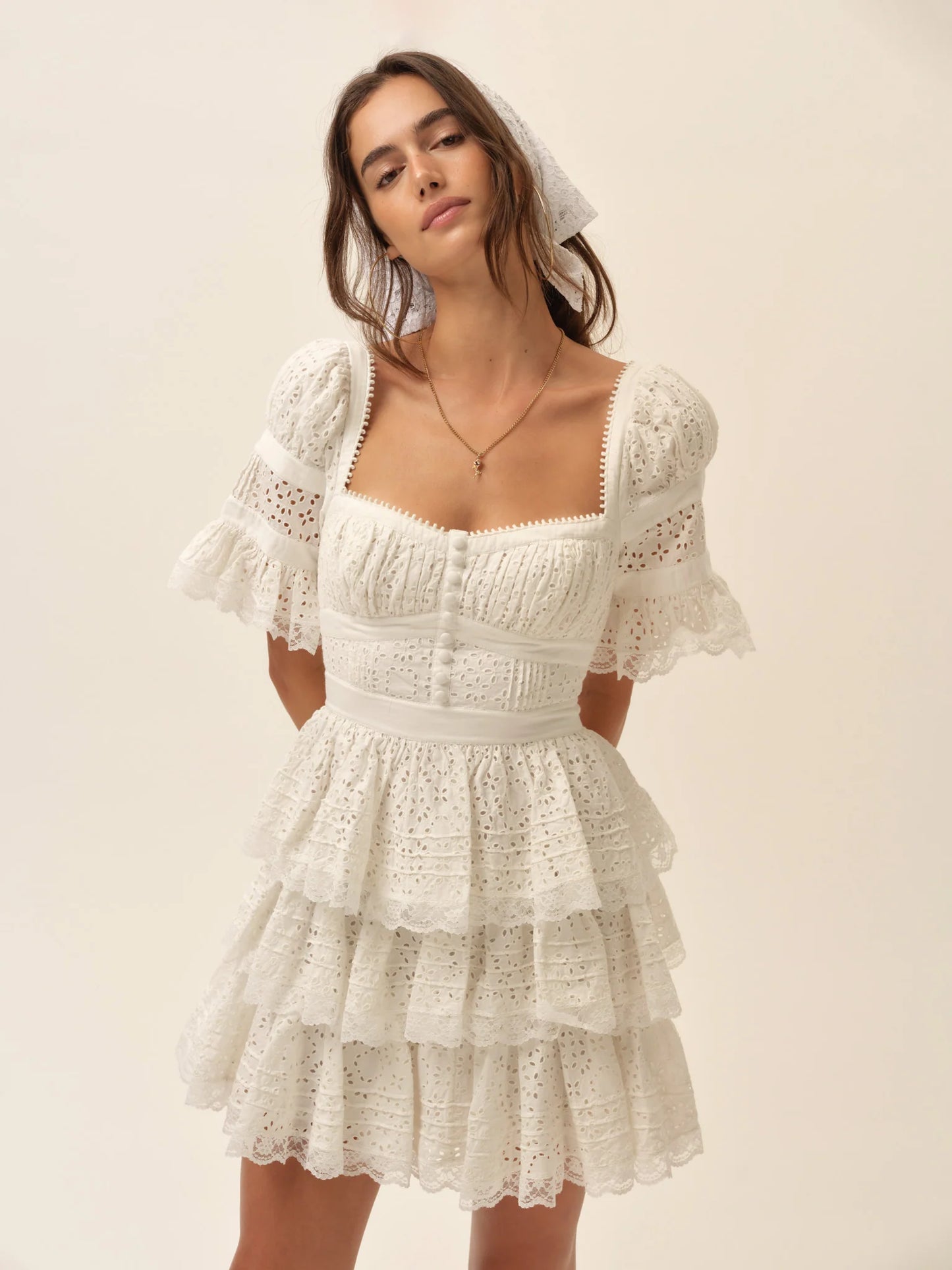 Model wearing the Willa Mini Dress in white featuring a square neckline, puff sleeves, corset-inspired bodice, and tiered ruffle mini skirt.