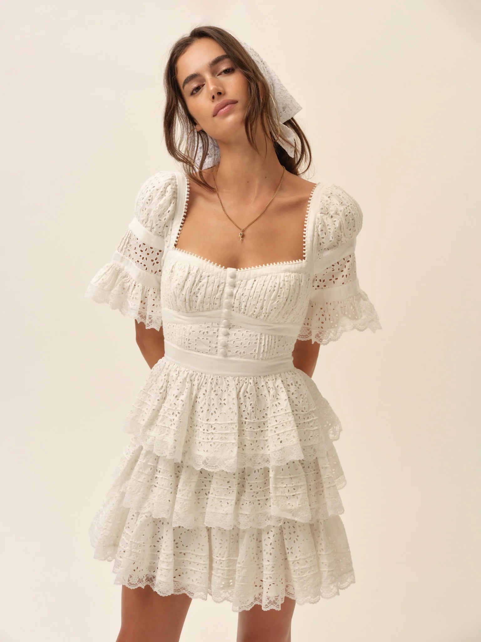 Model wearing the Willa Mini Dress in white featuring a square neckline, puff sleeves, corset-inspired bodice, and tiered ruffle mini skirt.