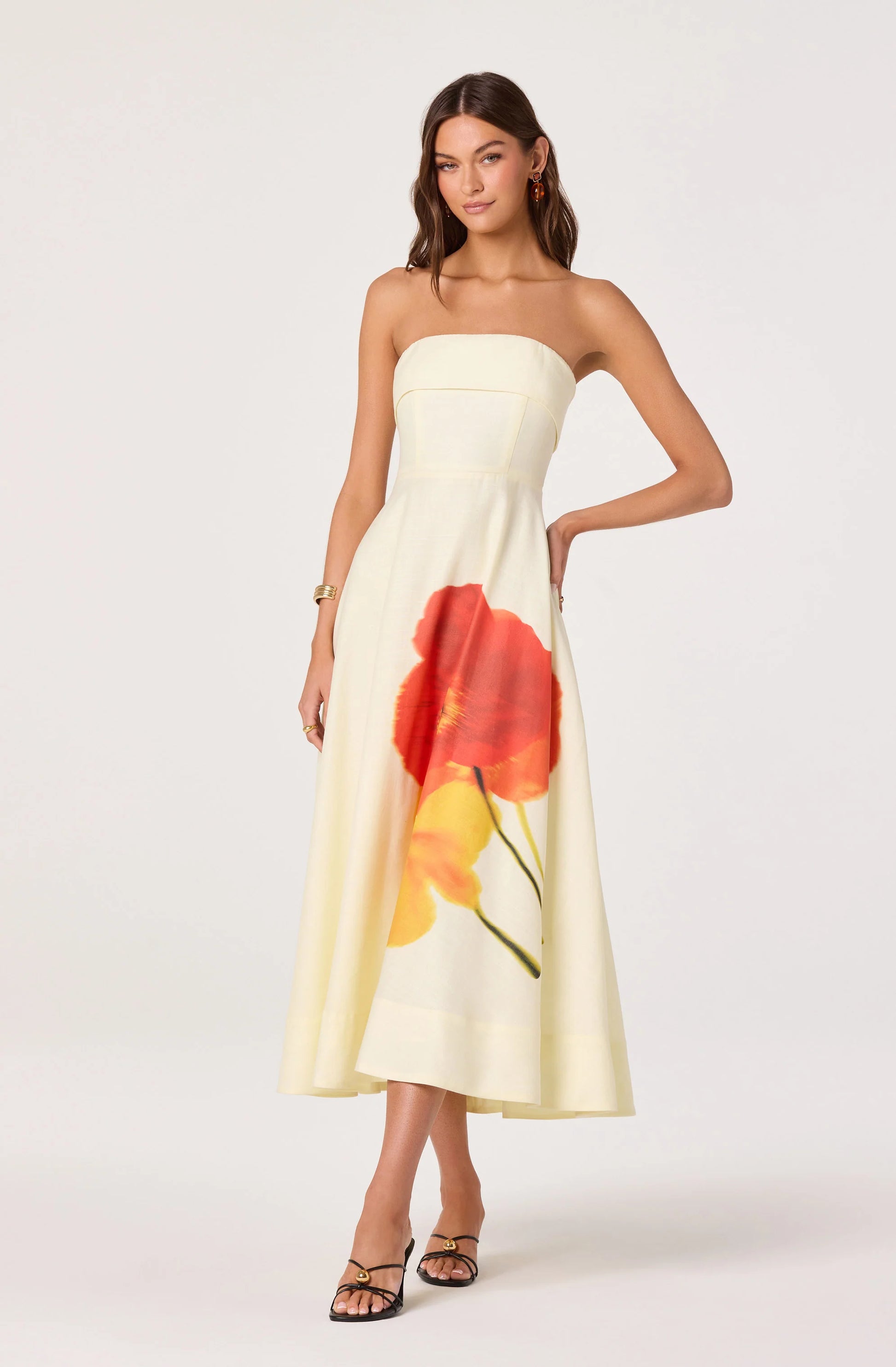 Model wearing the Ximena Floral Strapless Midi Dress in cream with a red and yellow floral placement print, shown from the front.