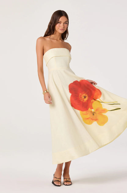 Model holding out the skirt of the Ximena Floral Strapless Midi Dress, showing the A-line shape and large red and yellow floral placement print.
