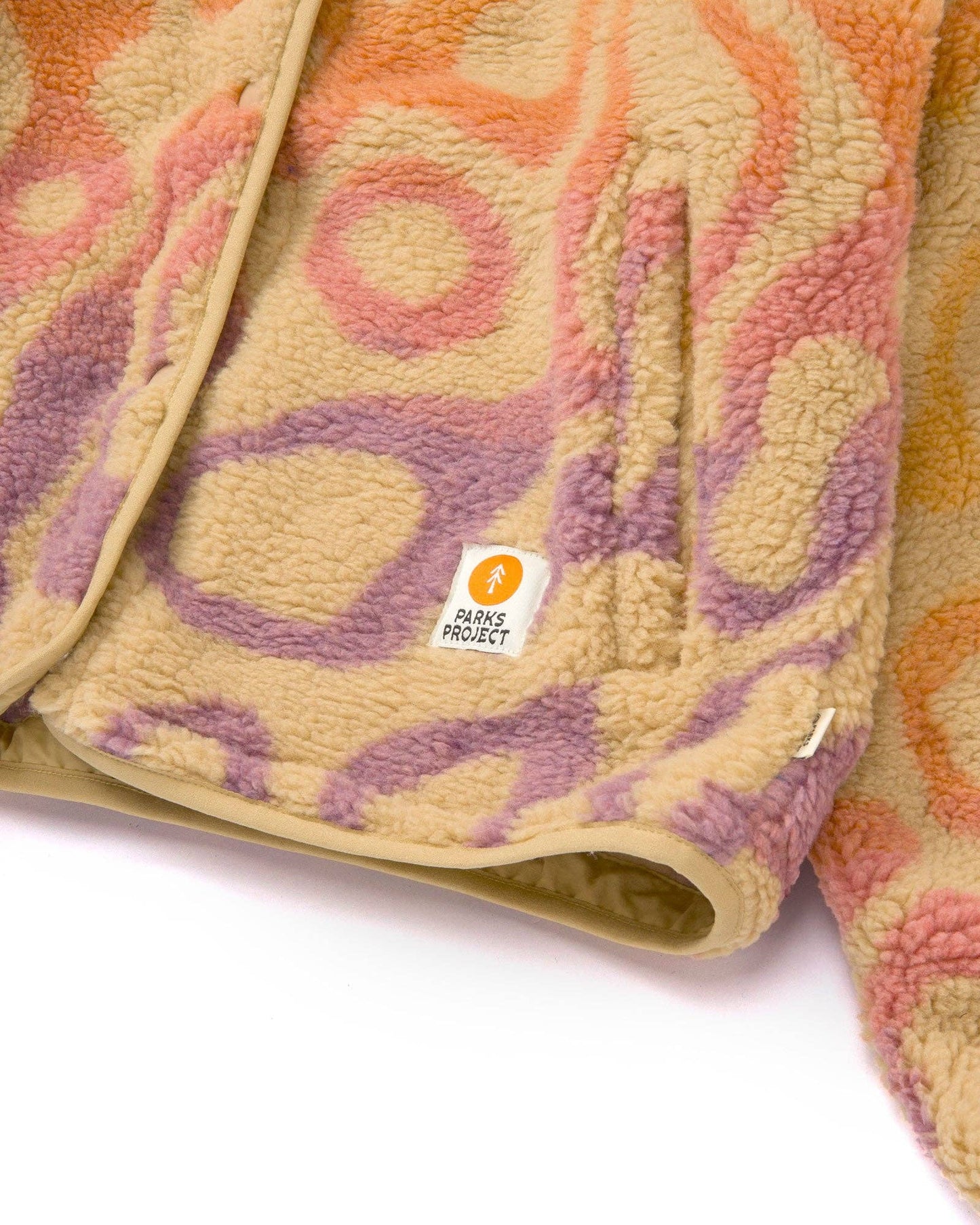 Close-up of the Yellowstone Geysers fleece jacket showing the jacquard texture, front pocket, snap detail, and elastic hem.