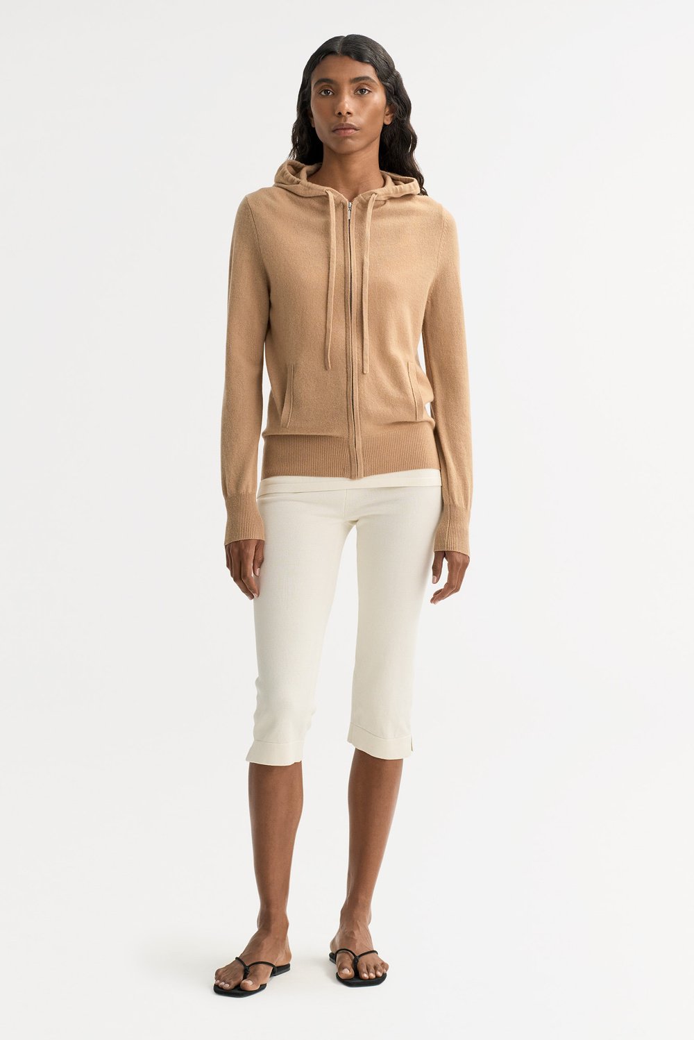 Model wearing a camel cashmere zip hoodie with cropped cream trousers for a refined casual look