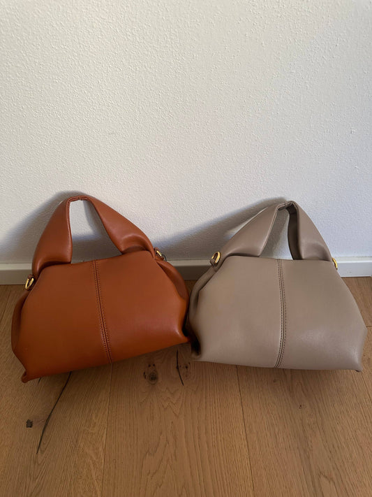 Two Zoe Premium genuine calf leather bags in cognac brown and taupe, shown side by side with padded top handles and gold-tone hardware.