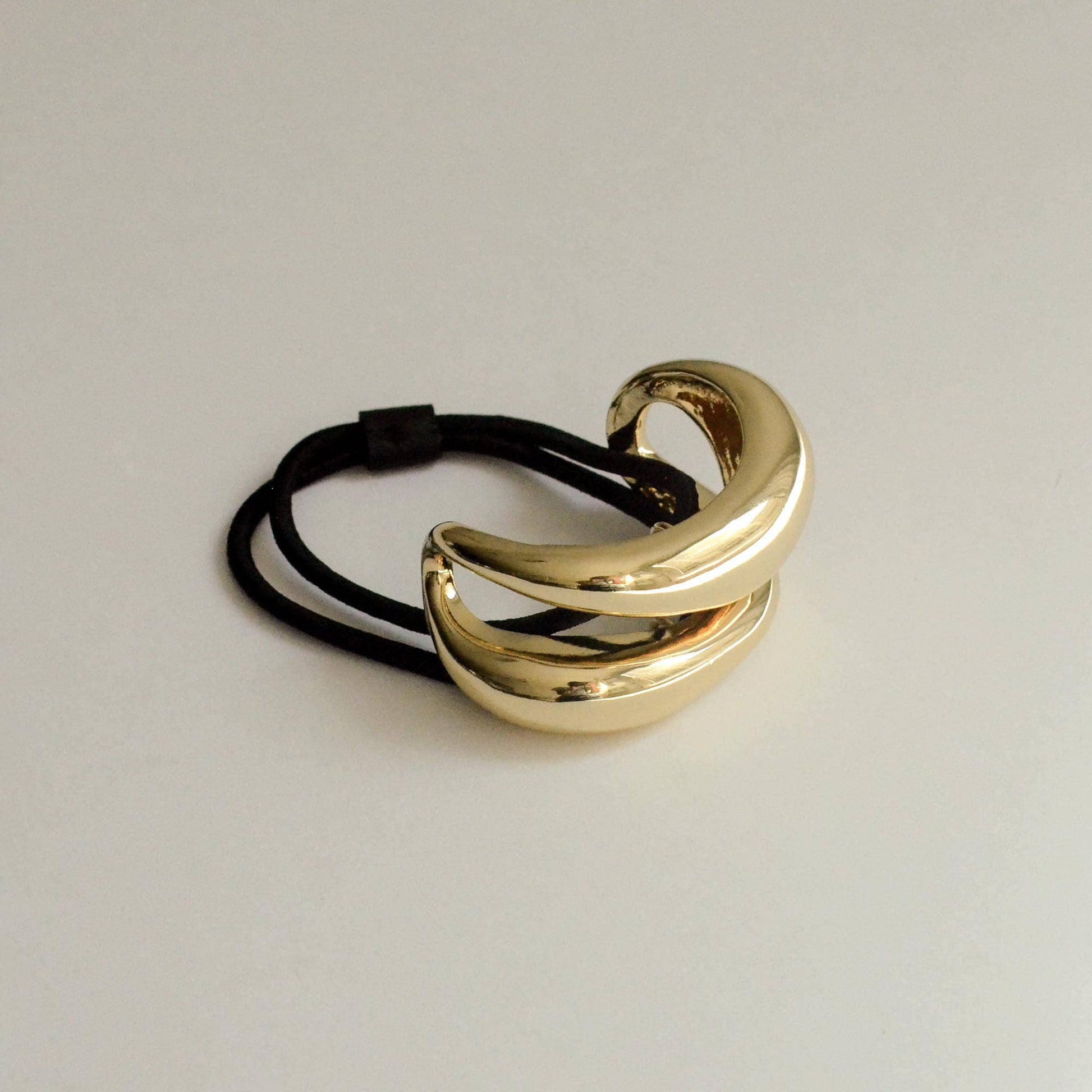 Wide sculptured gold metal ponytail hair tie with black elastic band