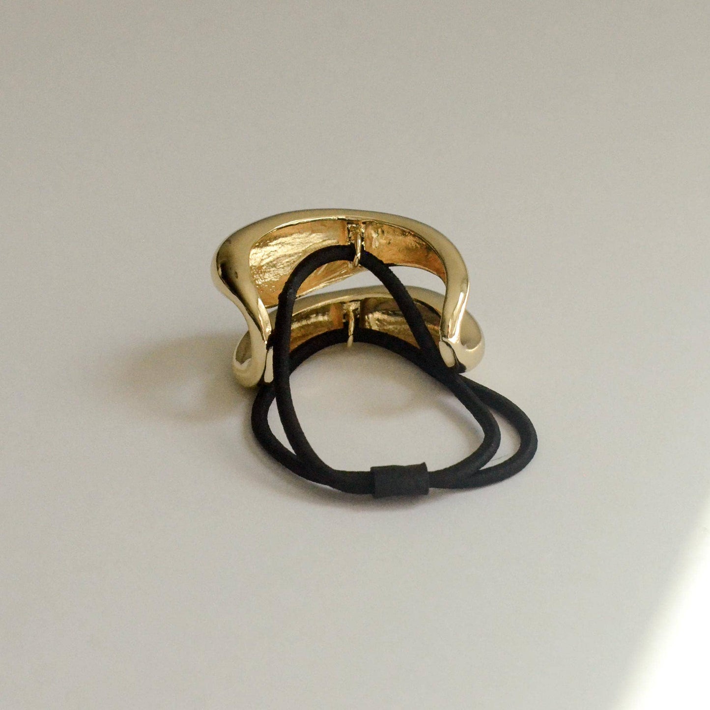 Back view of gold sculptured ponytail cuff with black elastic band