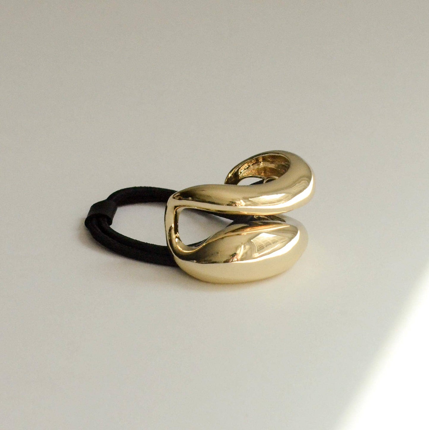 Side view of wide curved gold metal ponytail hair tie