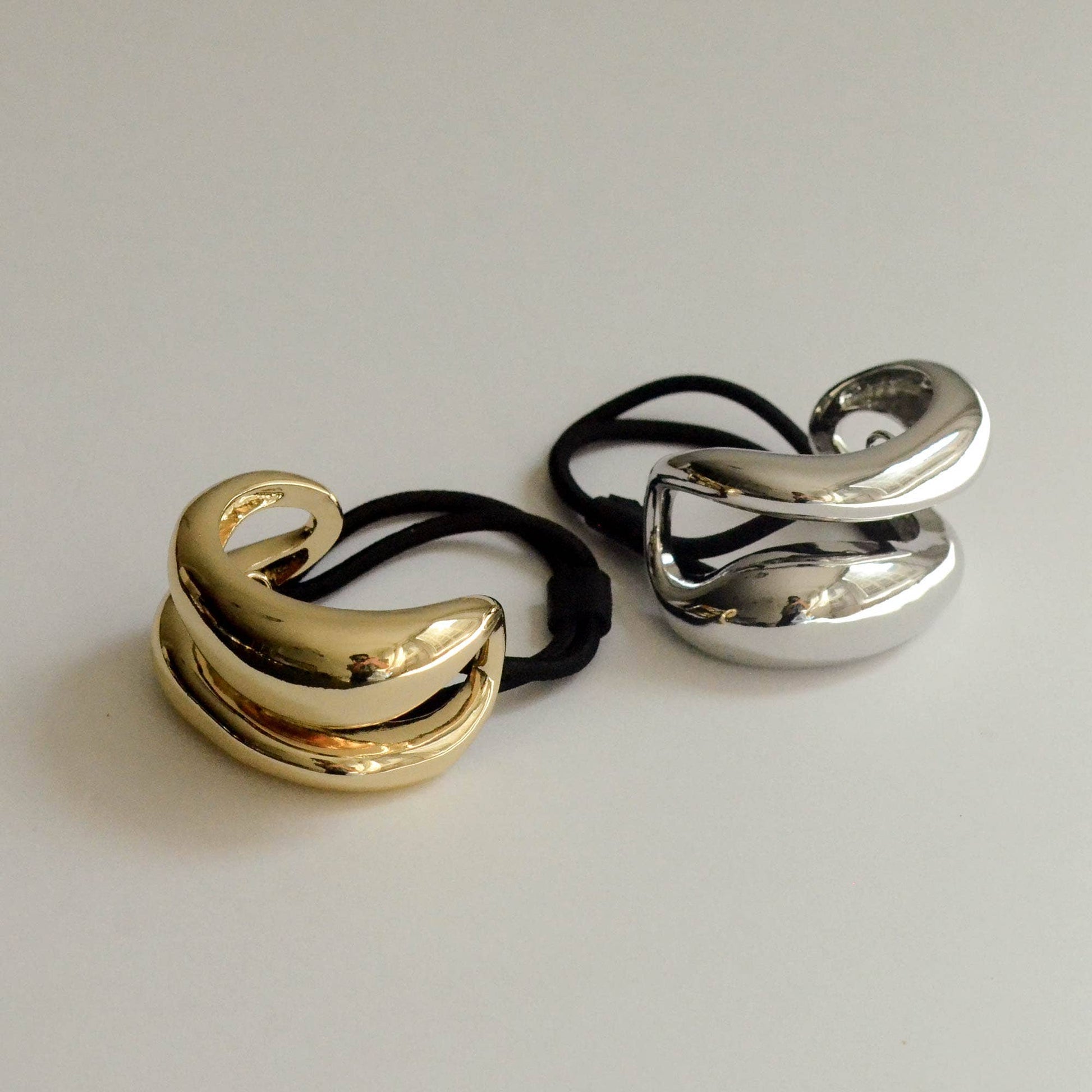Gold and silver wide sculptured metal ponytail hair ties shown together